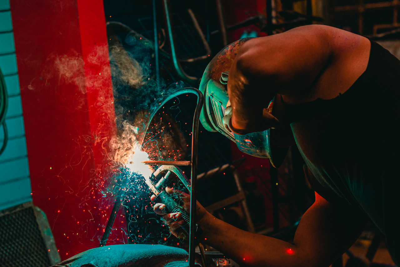 A welder skillfully works with sparks flying, captured in a Lima workshop.