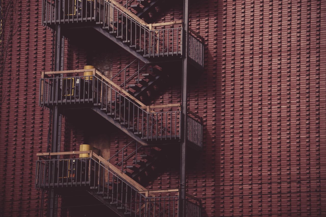 Fire escape ladder on a red brick wall, showcasing urban architecture and design.