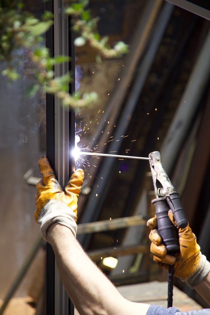 about-02 Close-up of a welder at work with sparks and protective gloves, showcasing skilled metalwork.
